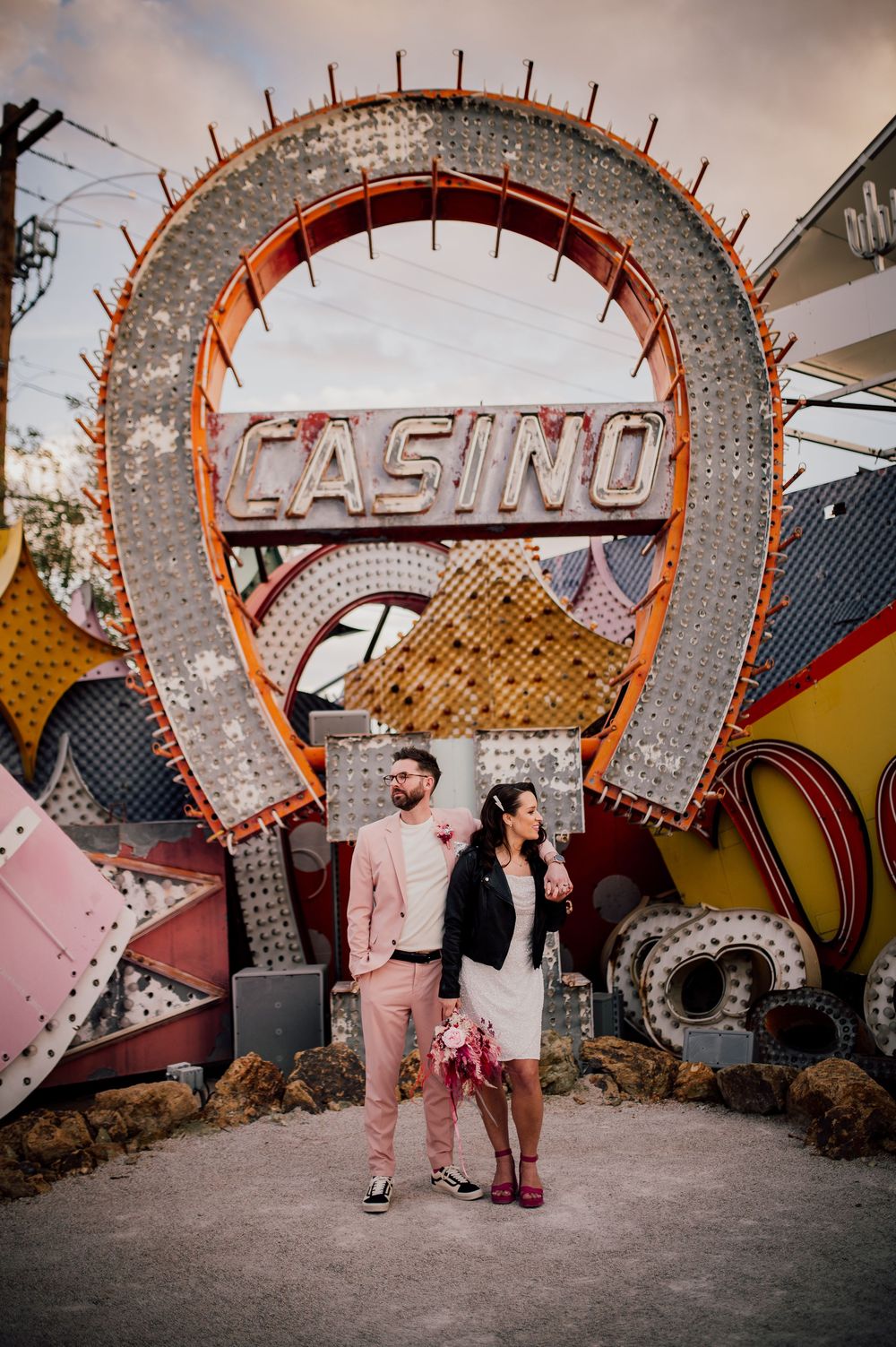 A series of photos showing a couple walking along a curved wall with vintage casino signage at the Neon Museum in Las Vegas.