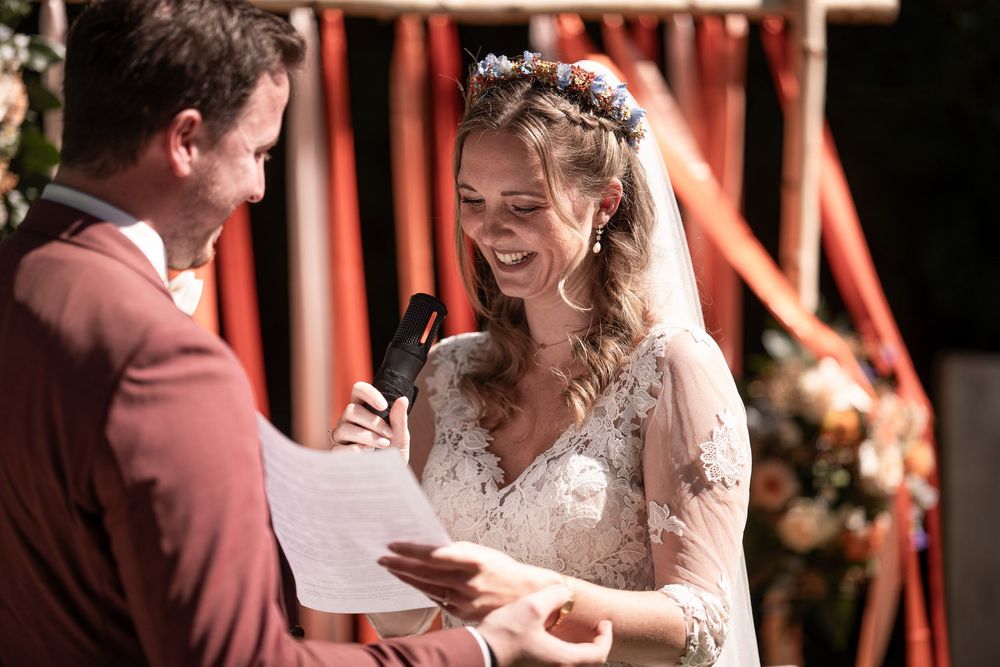 Trauung am Baumannshof: Brautpaar S&C hält Händchen während der Zeremonie im Freien. Authentischer Hochzeitsfotograf Kleve.