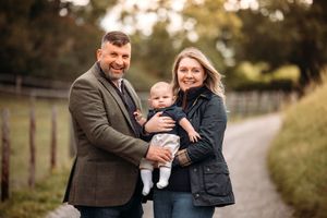 Family walking together on path during autumn photo session.