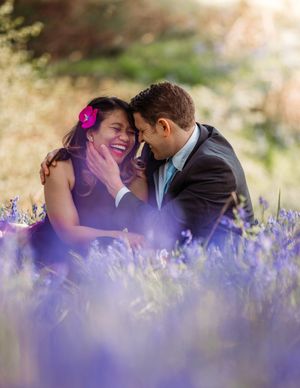Romantic couple sharing an intimate moment among purple wildflowers in a sunlit meadow.