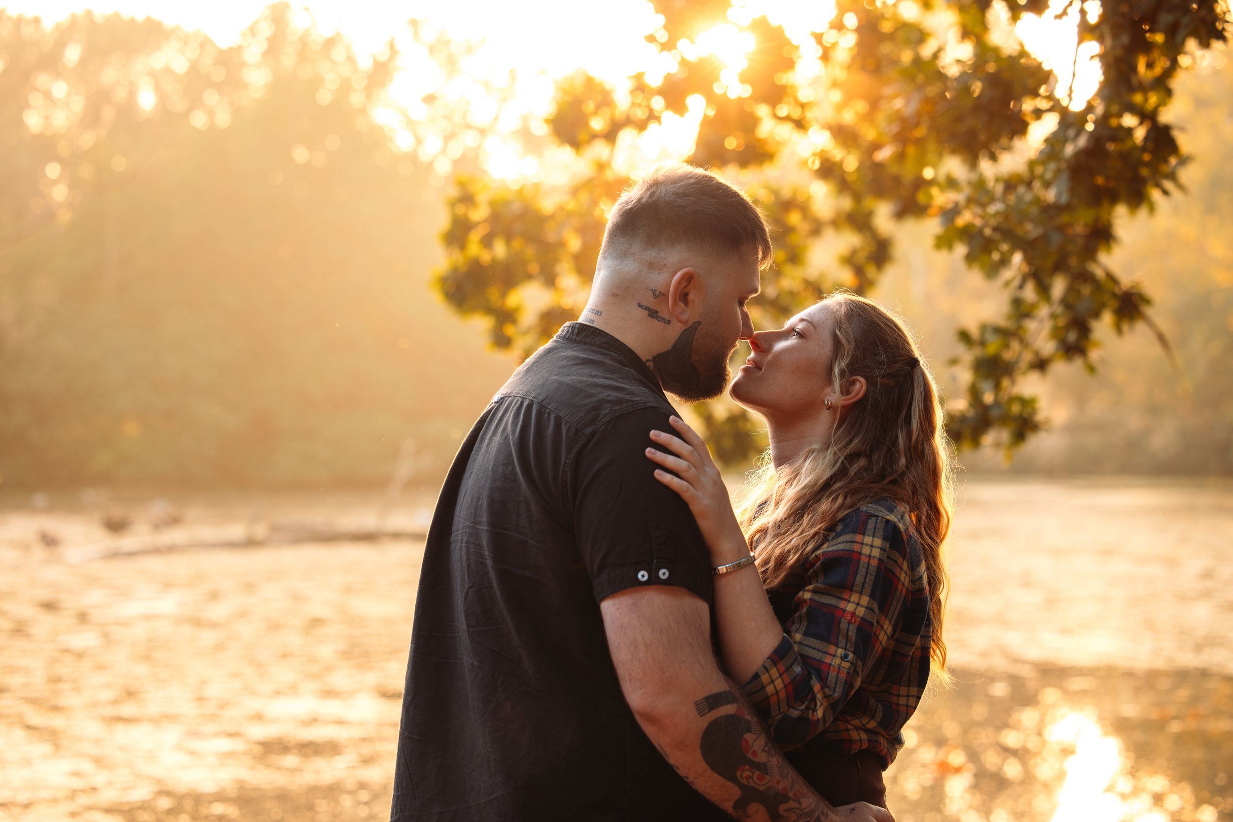 Couple walking together through autumn trees at sunset with golden backlighting.