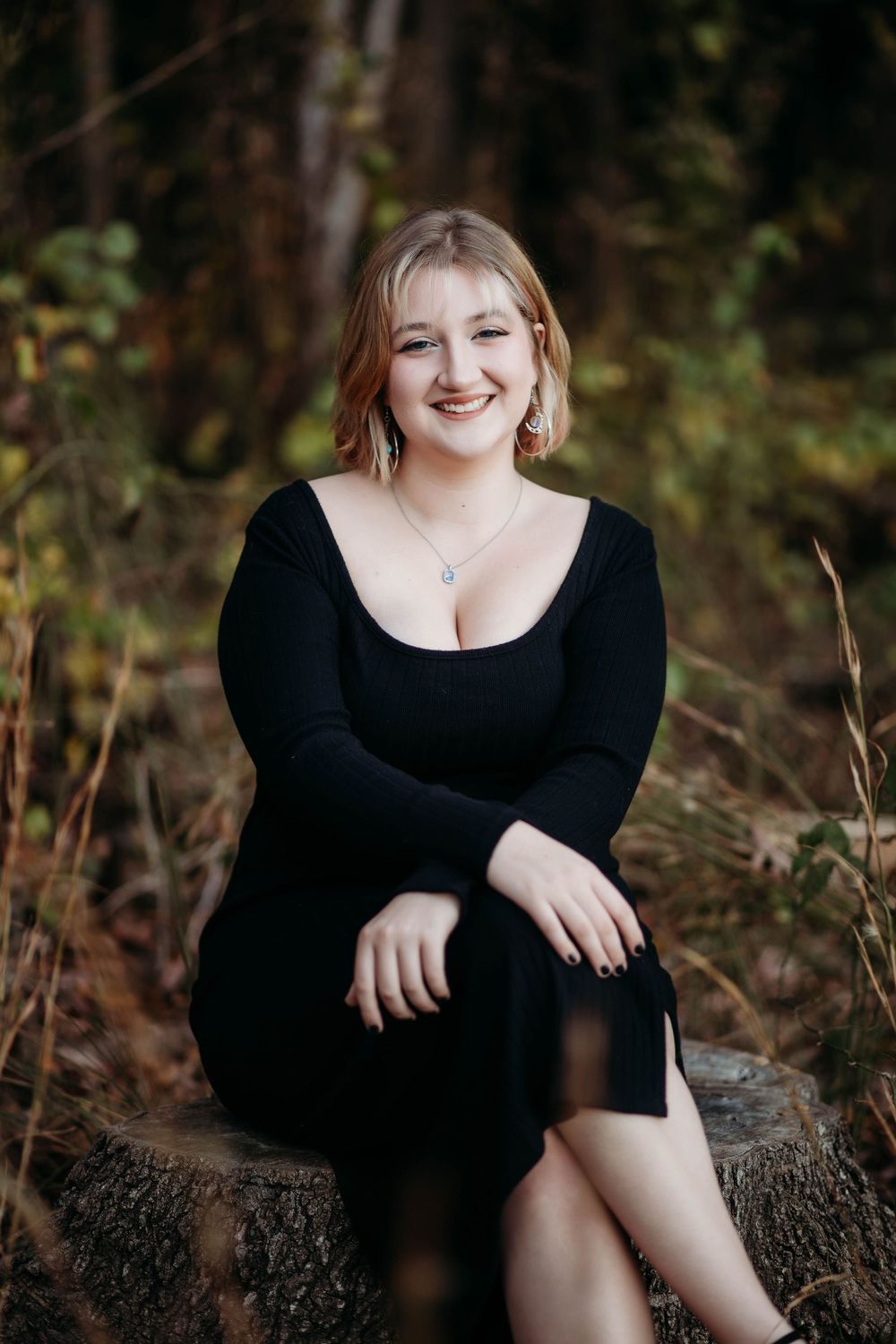 Outdoor portrait session in a wooded area wearing a black top against a natural background.