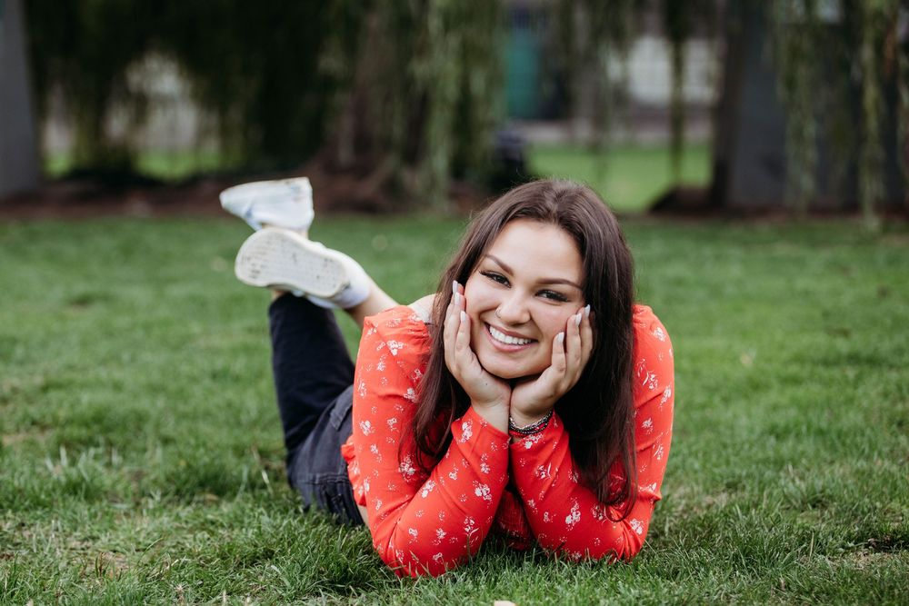 People lying on grass wearing red and white outfits during a casual outdoor photoshoot.