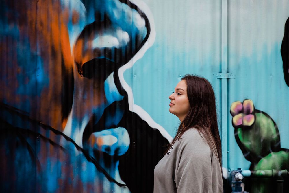 Urban portrait session against vibrant blue and orange graffiti wall.