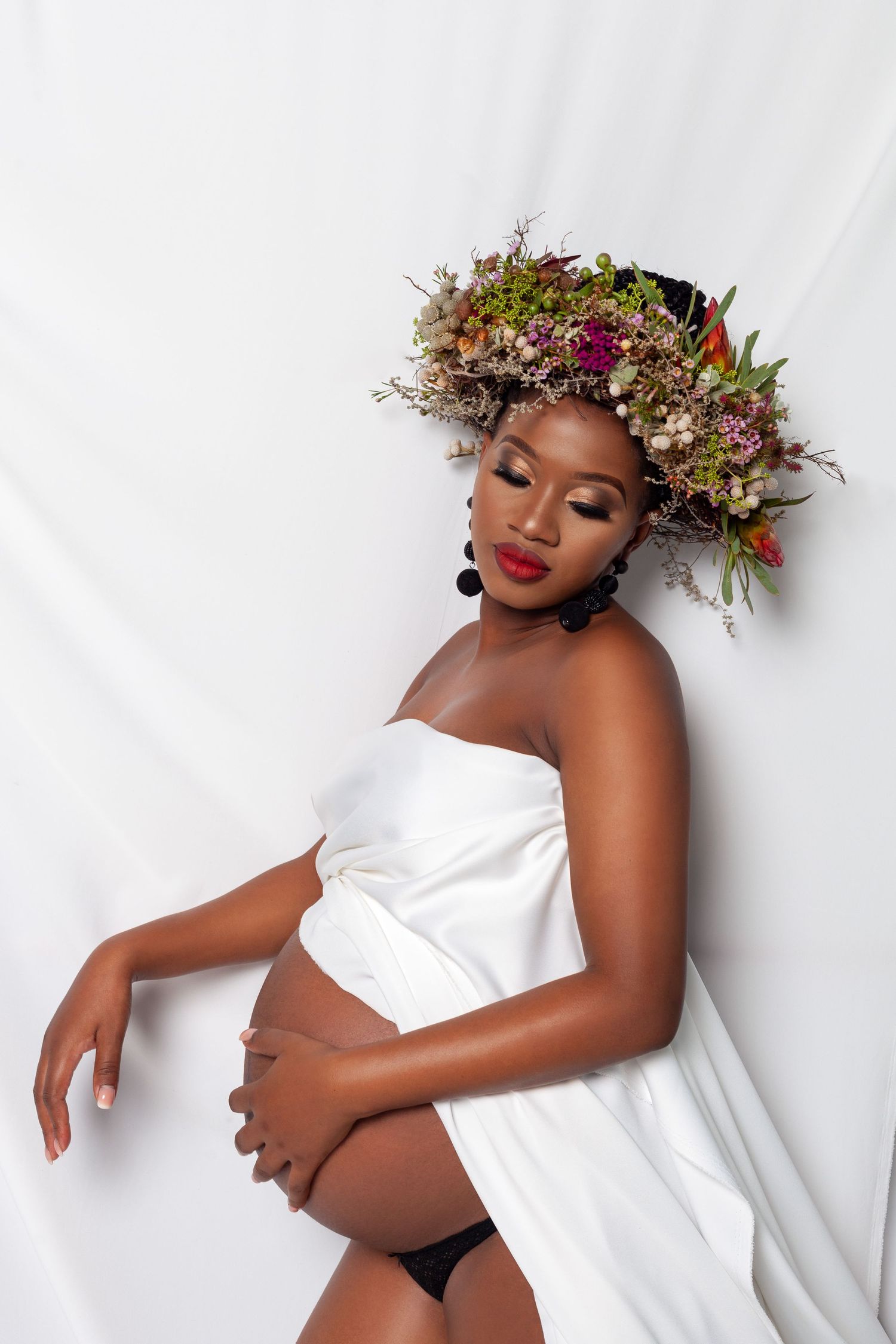 Artistic portrait series with floral crown and white fabric against light background.