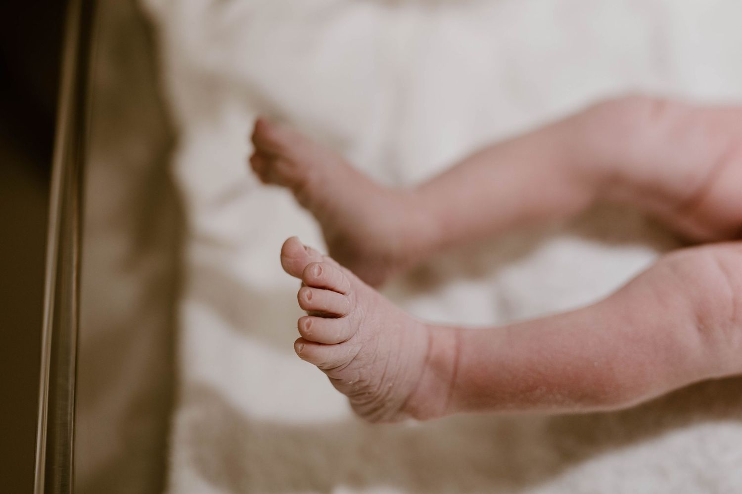 Close-up view of tiny baby feet and toes against a soft white background.
