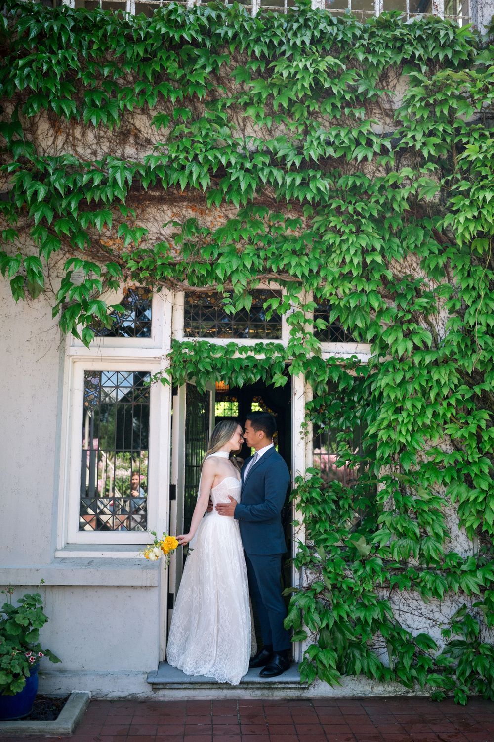 Bride and groom share a romantic moment in a doorway covered with lush green ivy on their wedding day.