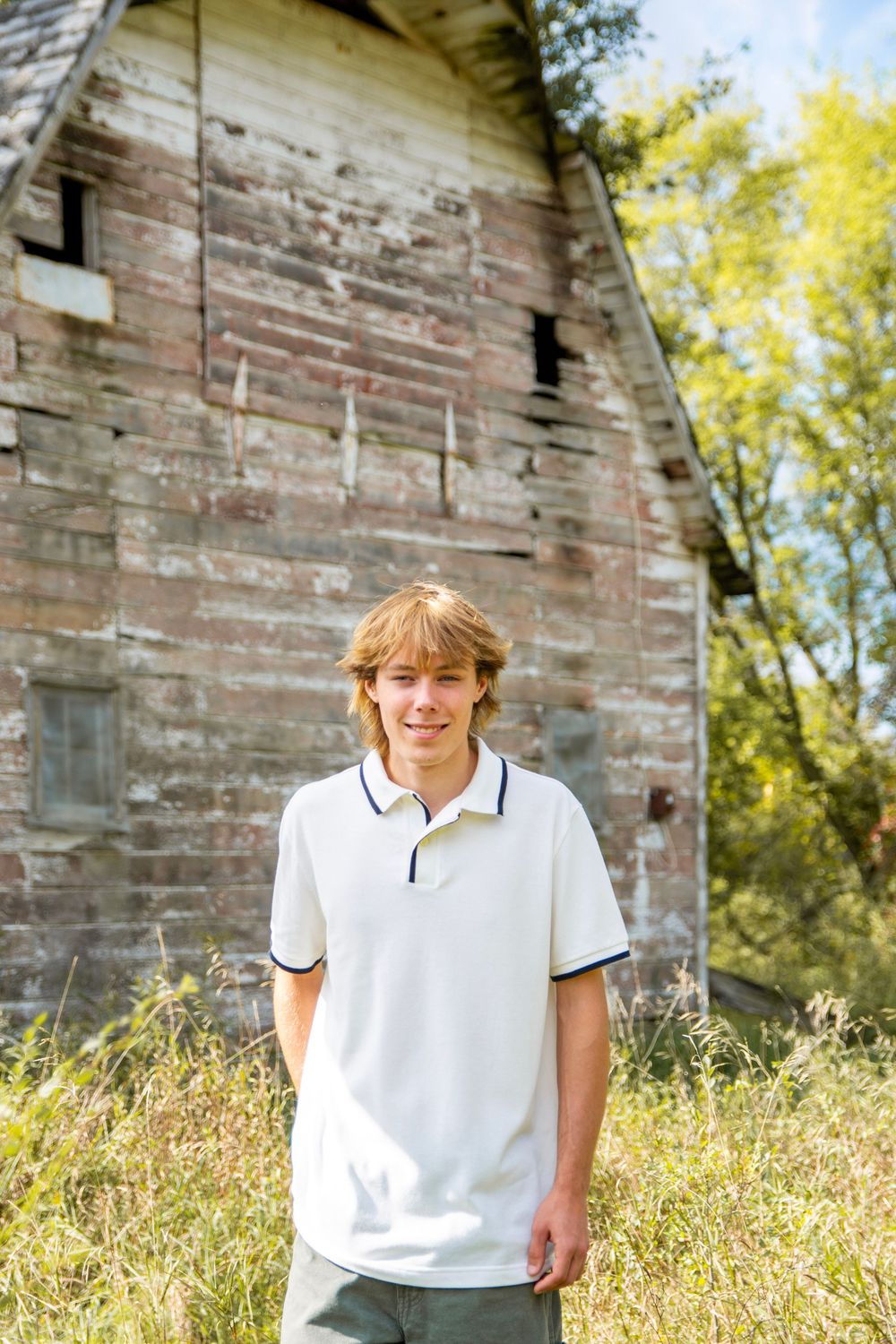 Outdoor portraits in front of a rustic brick building with tall grass in the foreground.