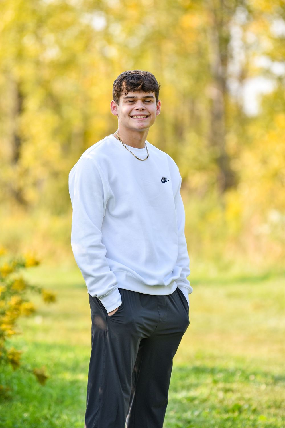 A casual autumn portrait featuring a white sweatshirt against golden fall foliage.