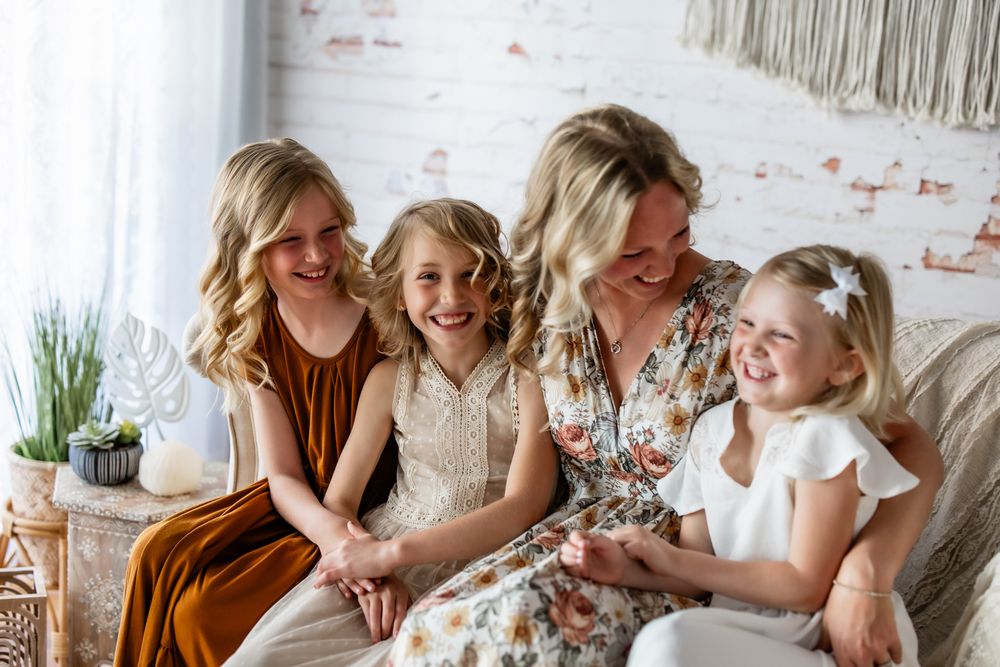 A group of people in white and floral dresses share joyful moments during a celebratory gathering.