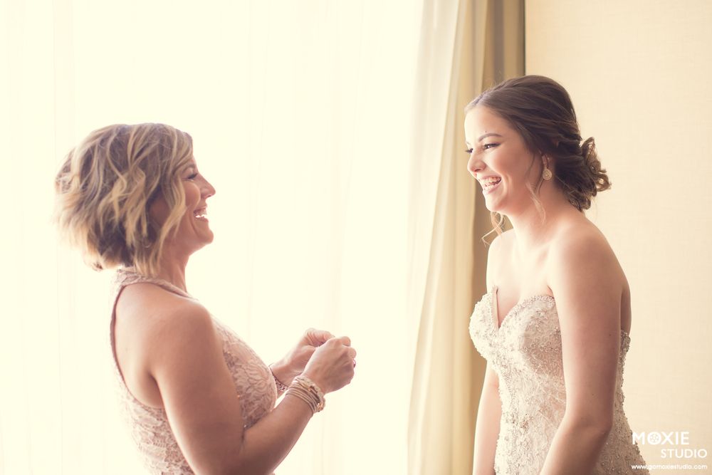 Two women share a joyful moment while preparing for a wedding ceremony.