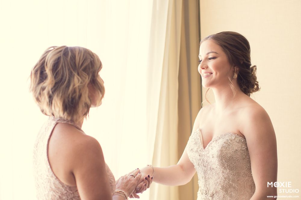Wedding party members share a tender moment while wearing elegant evening gowns.