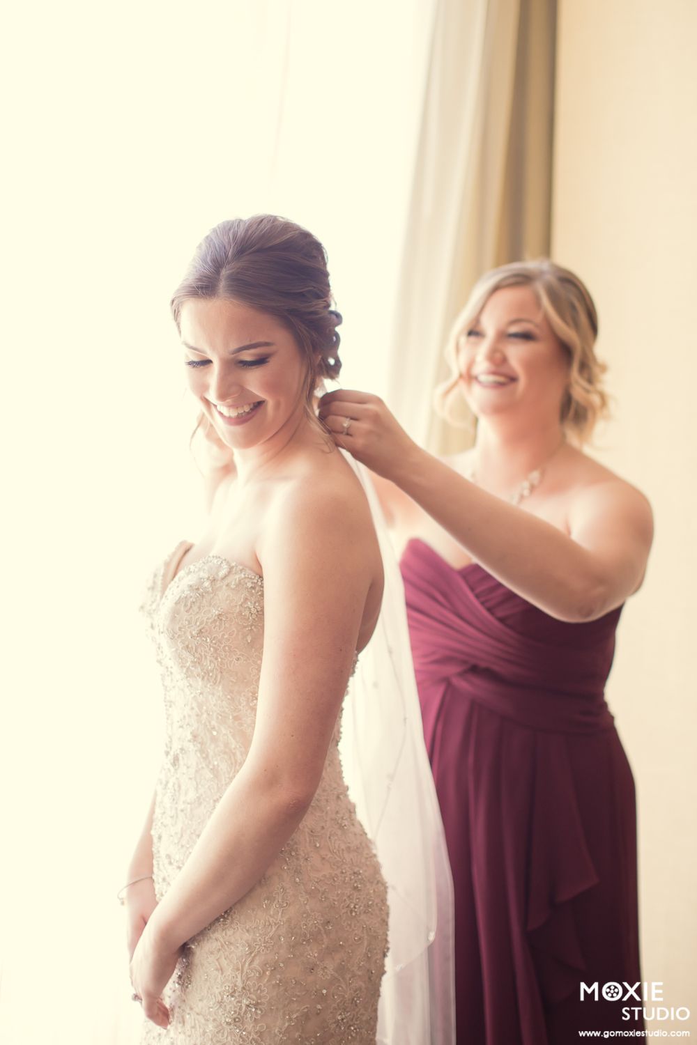 Emotional wedding preparation moment captured in soft natural window light.