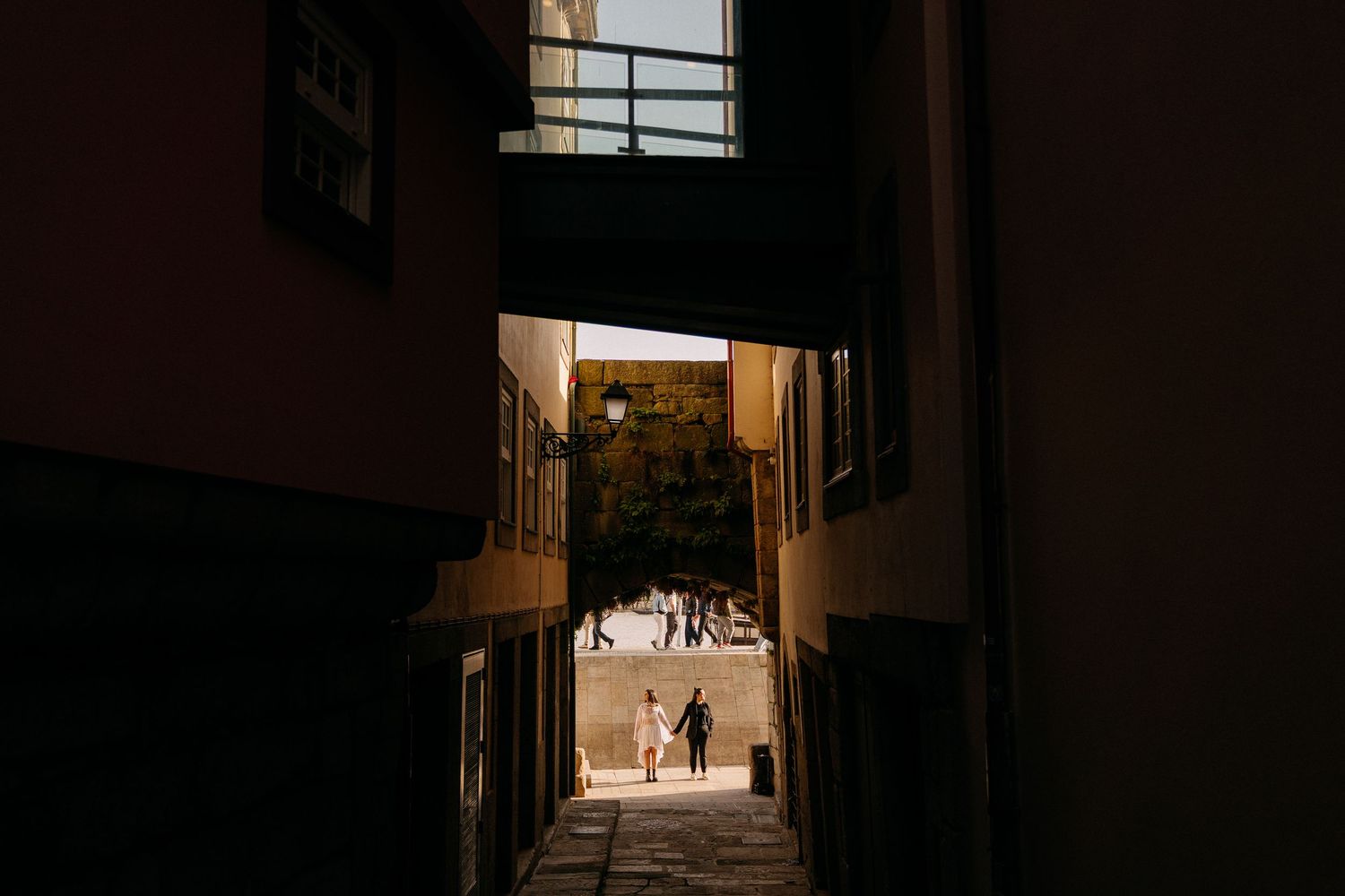 Dark urban alleyway with moody lighting and shadows cast between buildings at night.