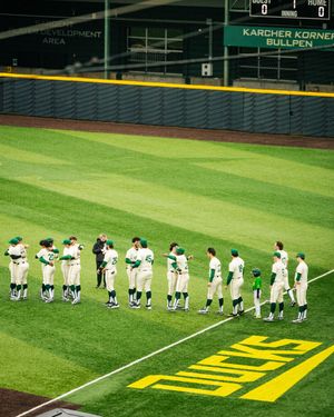 Baseball team players lined up on a green field with yellow text painted on the grass.