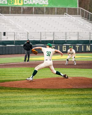 Baseball pitcher in white and green uniform number 37 mid-throw on pitching mound during game.