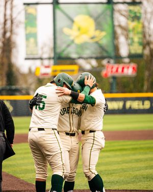 Baseball players huddle together in a team meeting on a green baseball field during a sunny day.