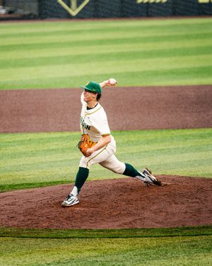 Baseball pitcher in mid-delivery motion on the mound during a game.
