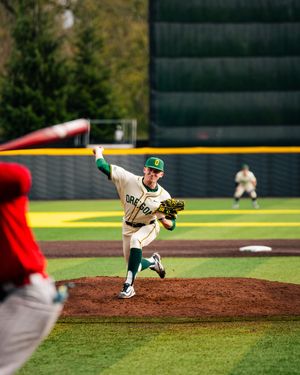 Baseball pitcher in mid-delivery motion on pitcher's mound during daytime game.