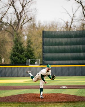 Pitcher in white uniform throws from the mound during a baseball game.