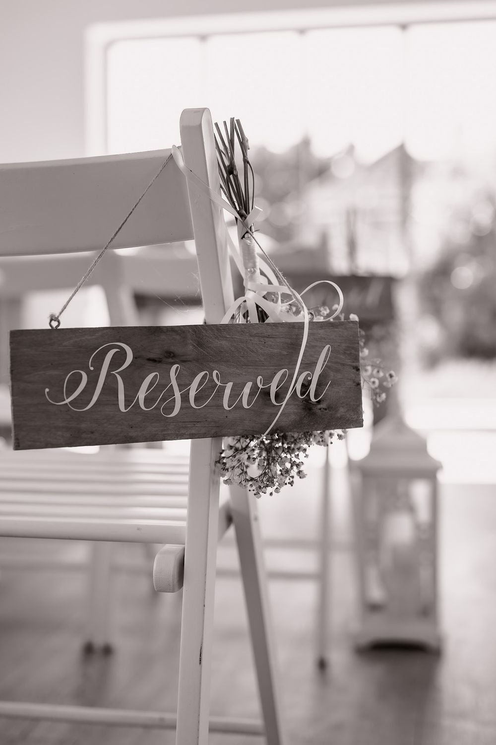 Reserved seating sign in elegant script on rustic wooden board with floral accents.