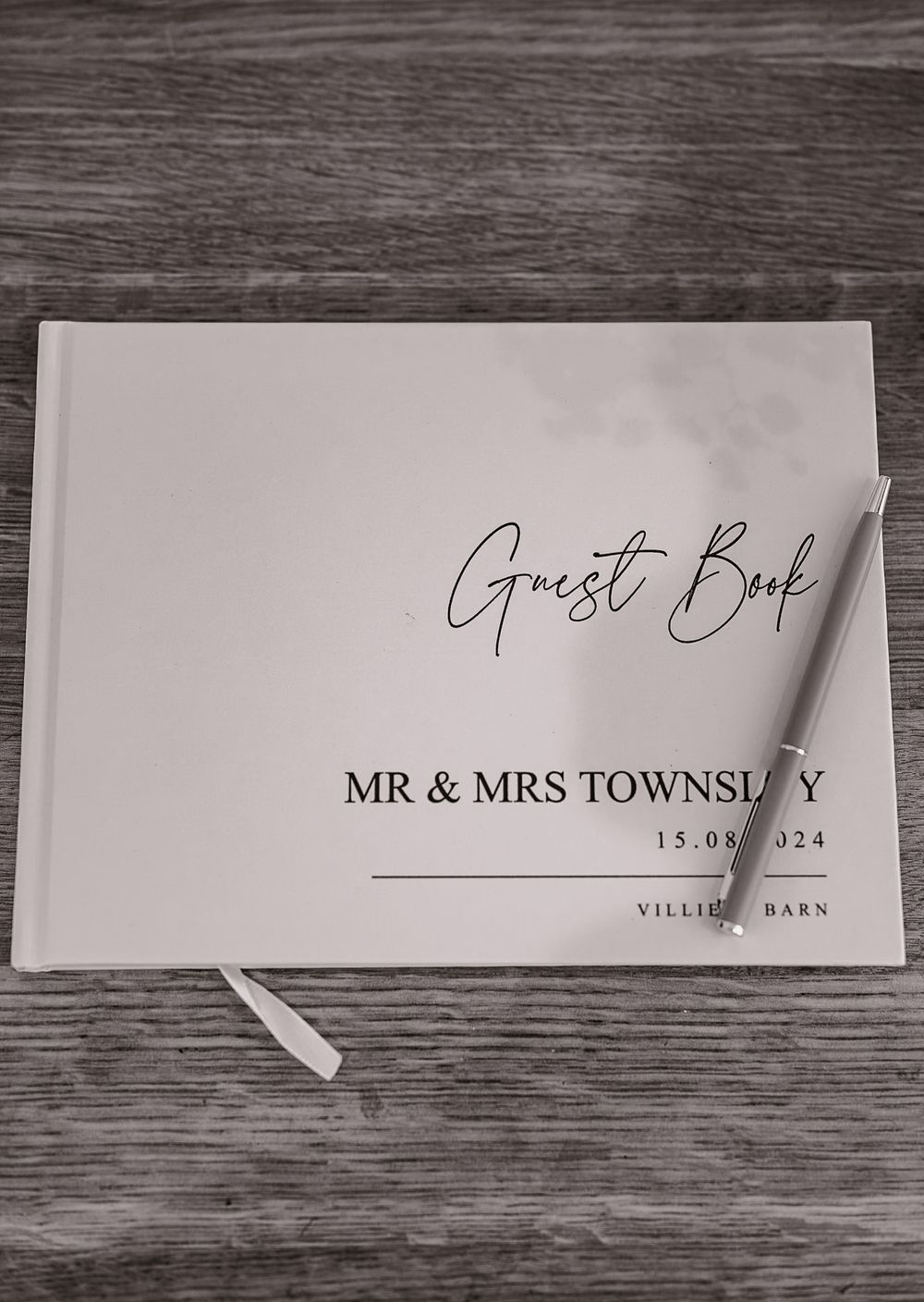 Wedding guest book and place cards displayed on dark wooden surface with elegant calligraphy.