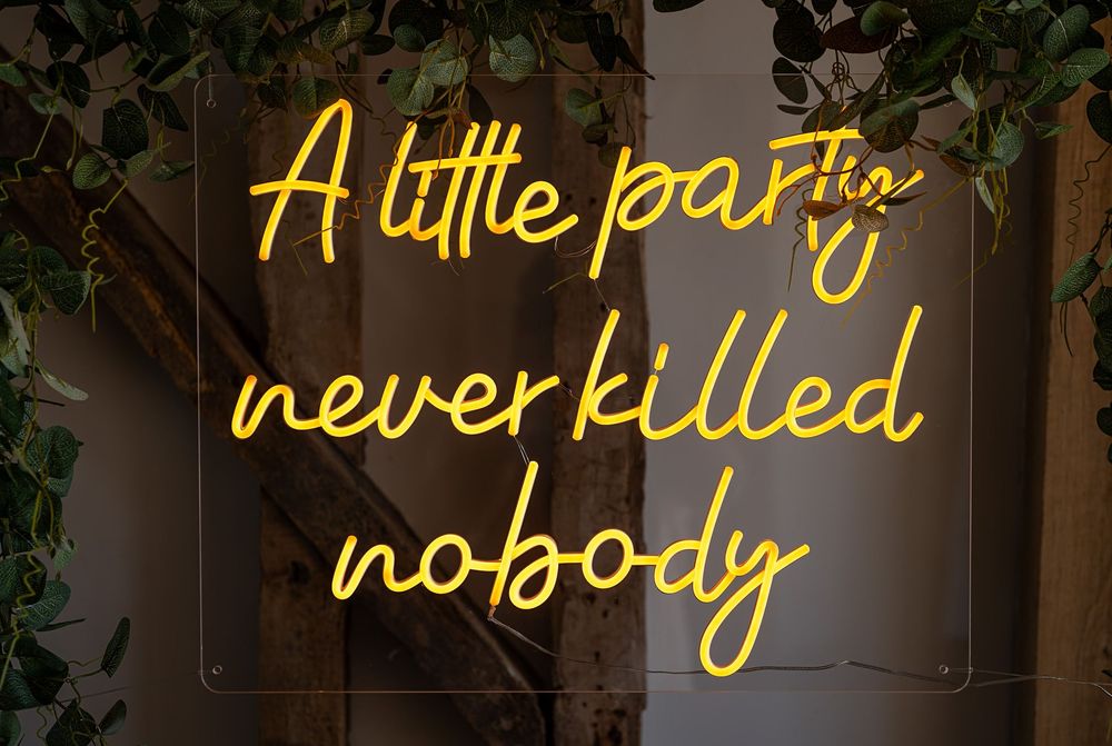 Yellow neon signs displaying text against a dark background with greenery.