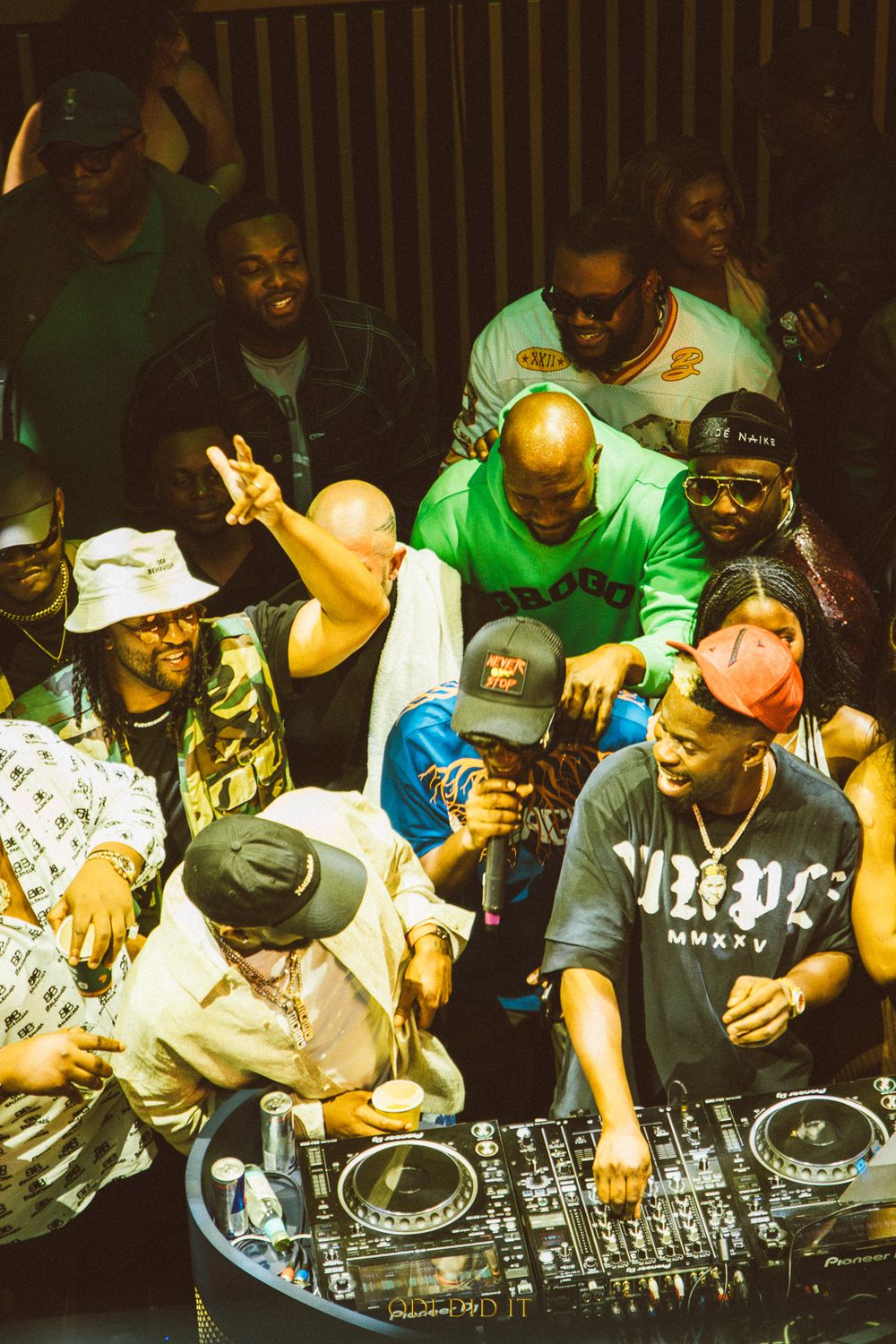 DJs perform at turntables during a nightclub event while others watch and engage with the music.