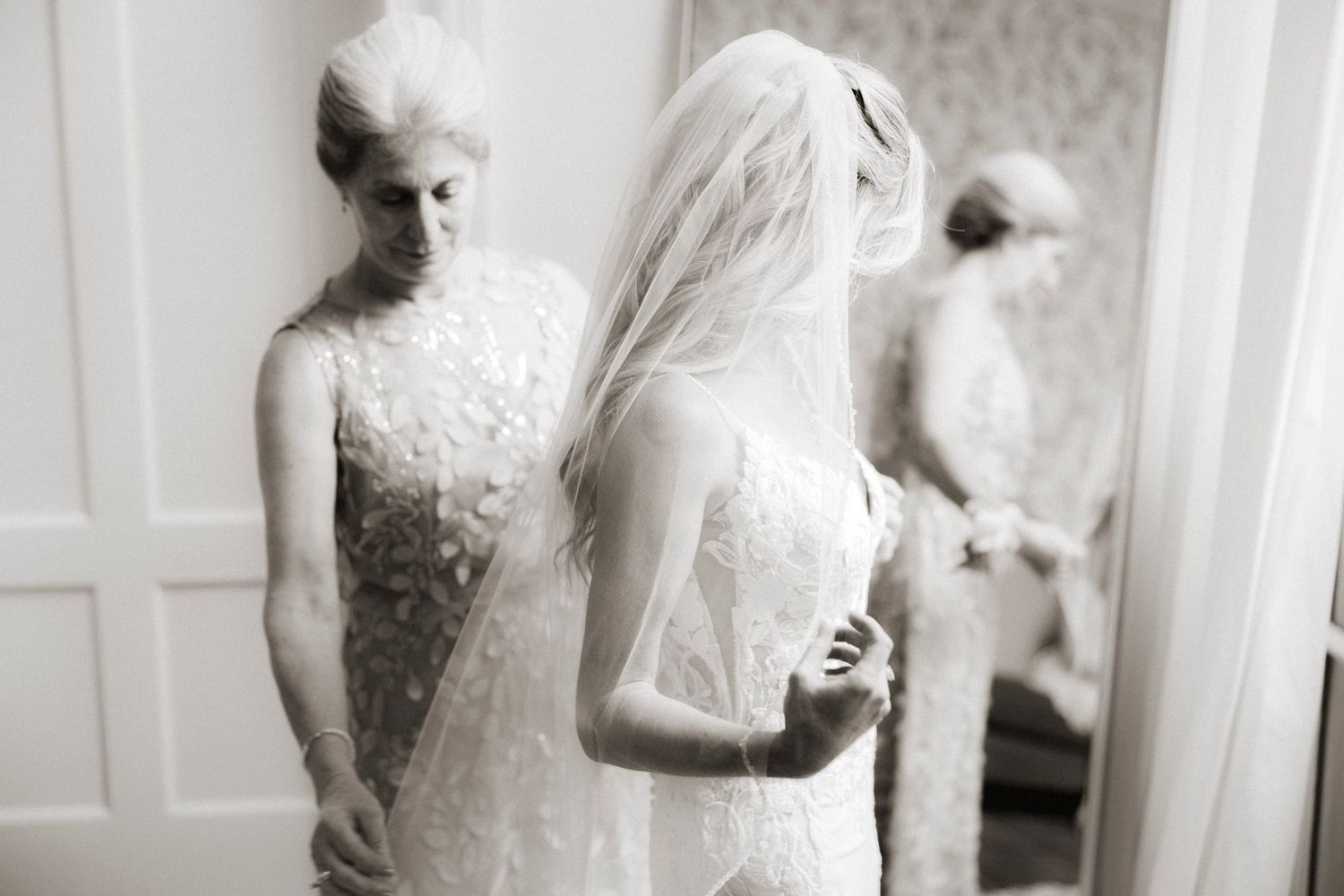A collection of black and white wedding photos showing details of a lace dress and intimate moments during preparation.