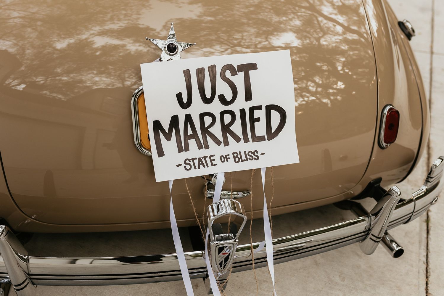 A vintage car hoods in beige and brown tones with a Just Married sign displayed at a wedding at The Oaks at Duncan Lane.