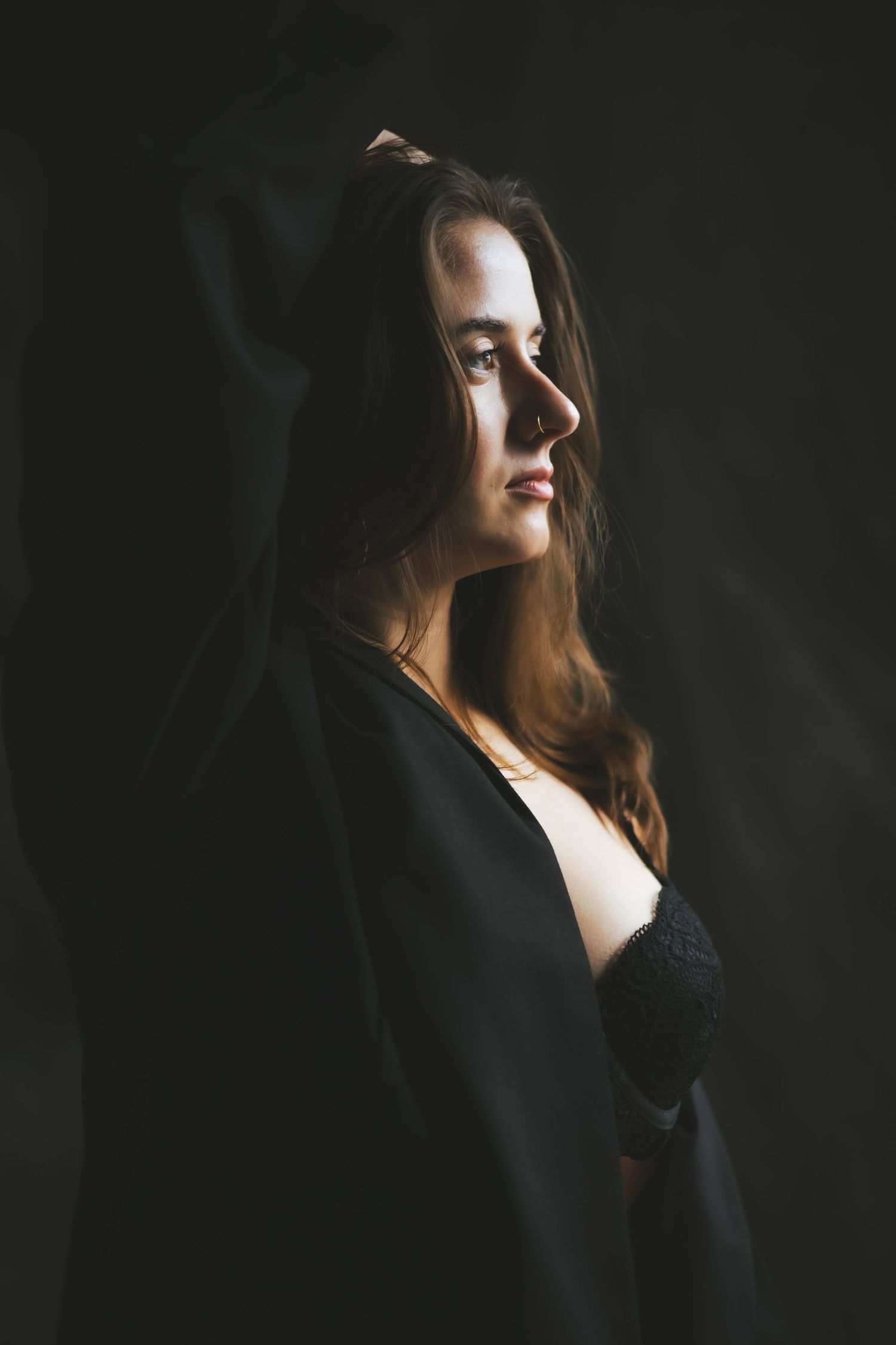 Close-up detail of delicate lace and satin lingerie with gold butterfly embellishments against dark fabric.