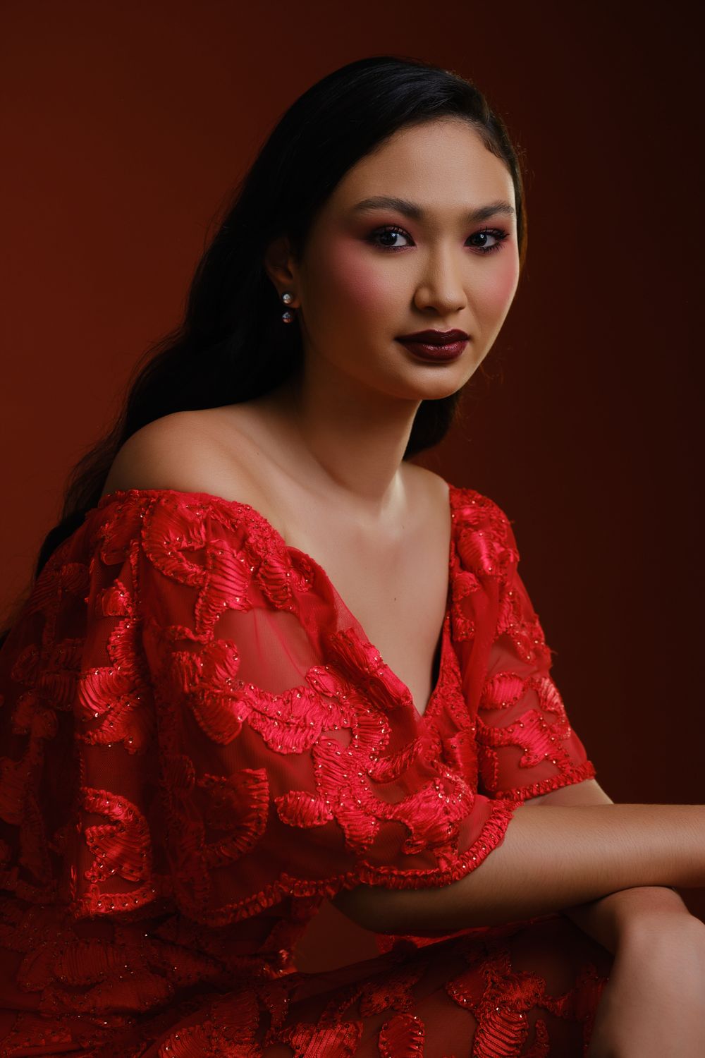 Portrait de Hiilei, modèle de la Tahiti Fashion Week, en robe rouge, sur un fond rouge, en studio.