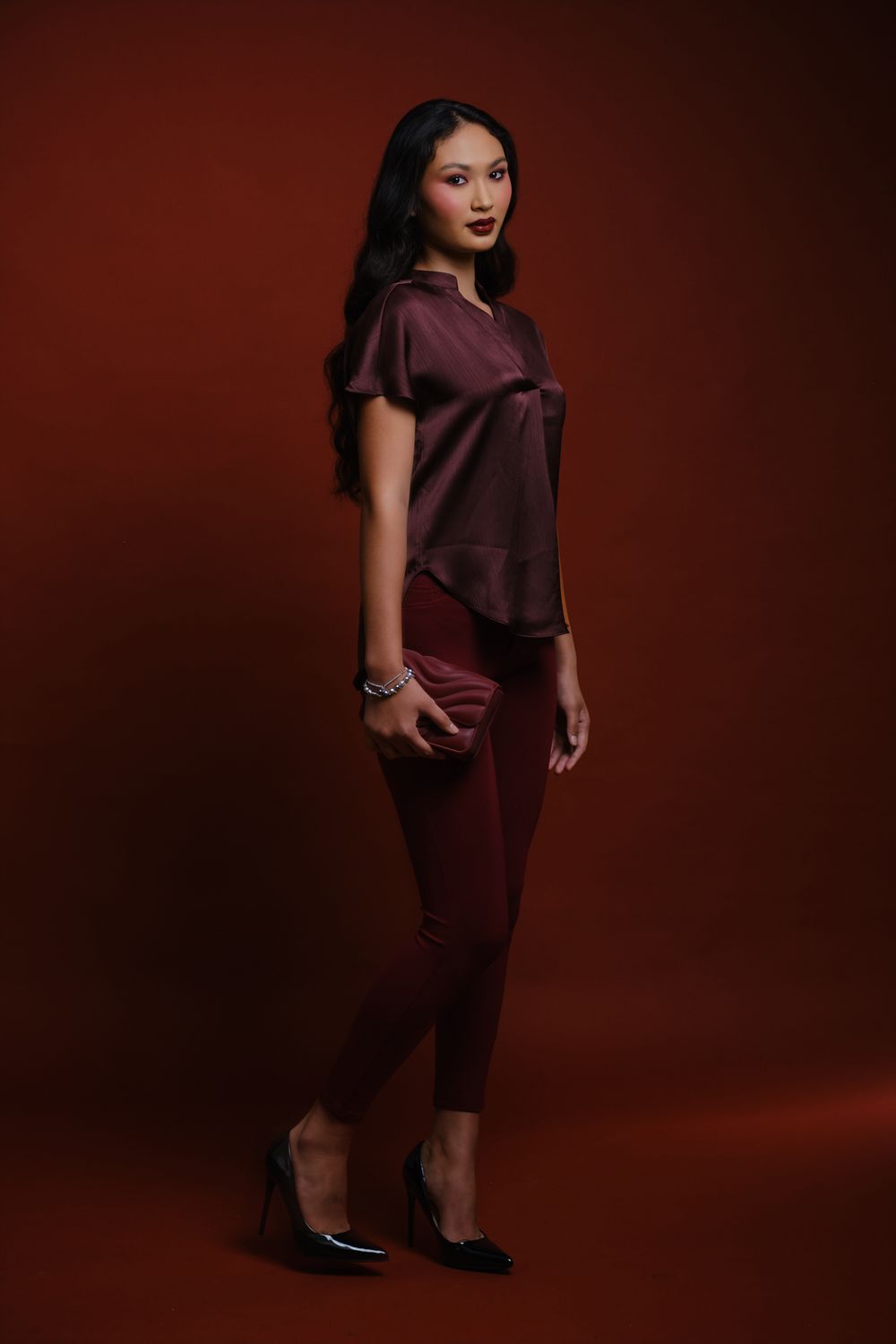 Hiilei, modèle de la Tahiti Fashion Week, de plein pied, en pantalon rouge, sur un fond rouge, en studio.