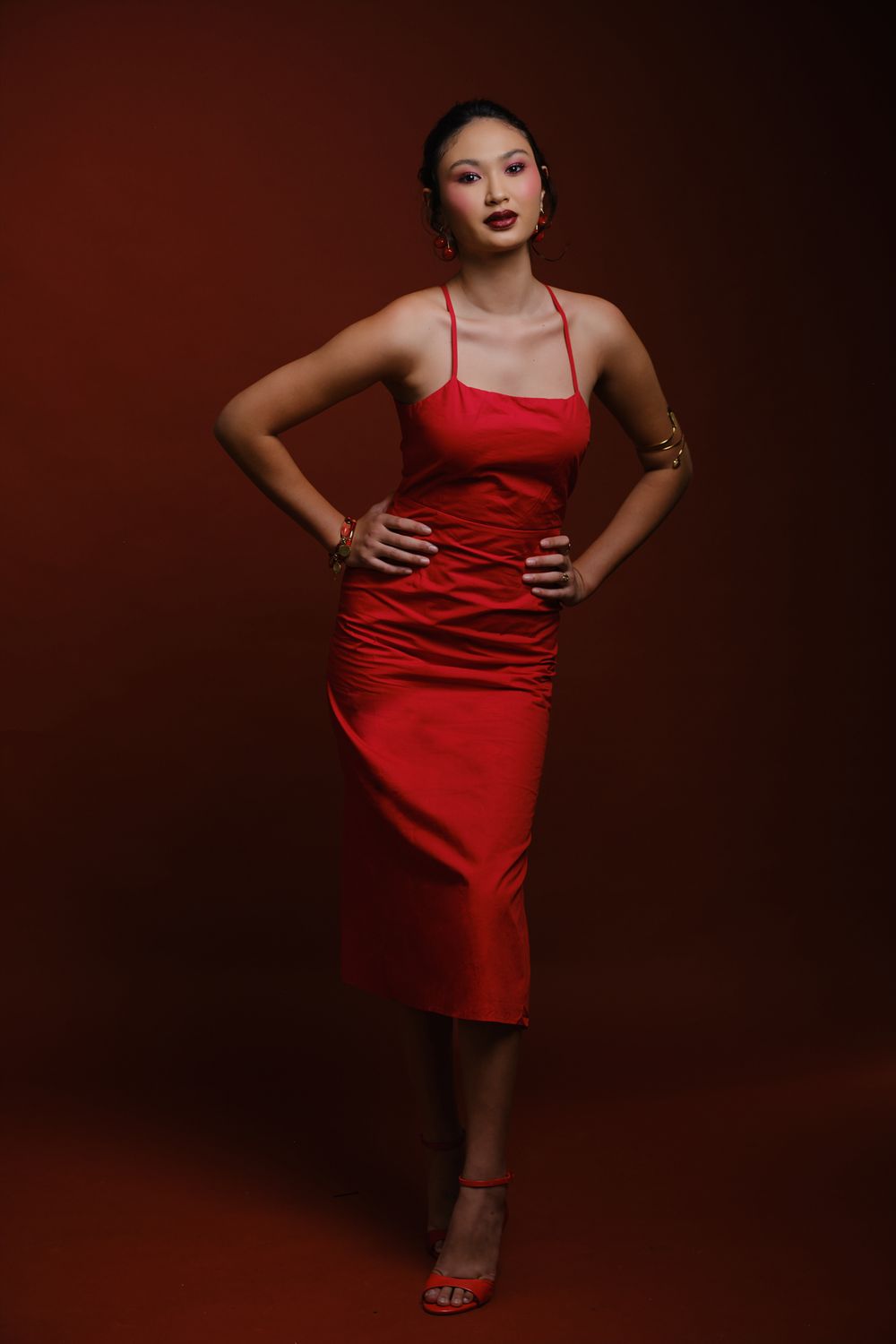 Hiilei, modèle de la Tahiti Fashion Week, de plein pied, en robe rouge, sur un fond rouge, en studio.