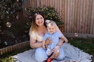 Family photo session in a backyard garden with wooden fence backdrop.