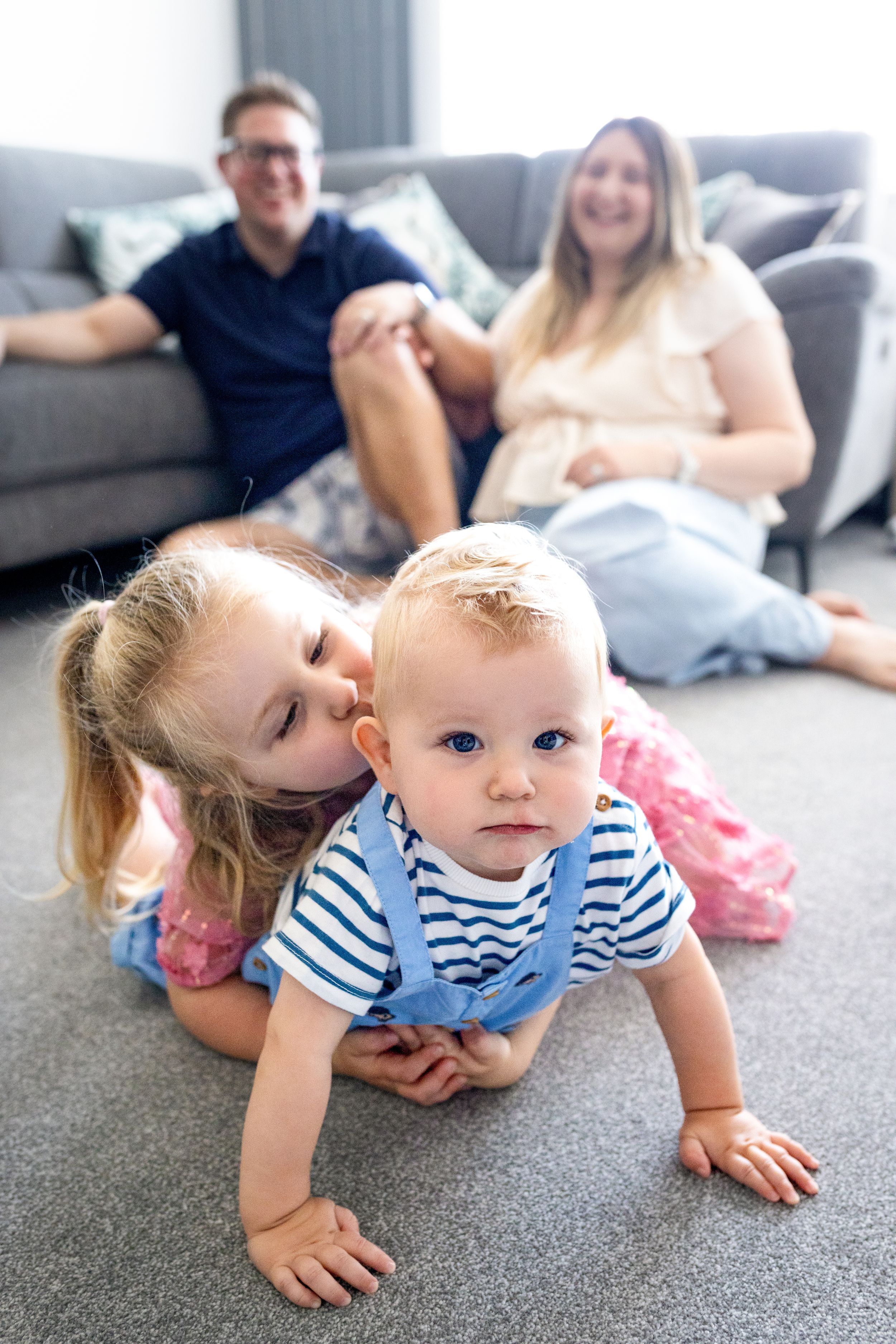 A playful moment captured on a grey carpet in a living room setting.