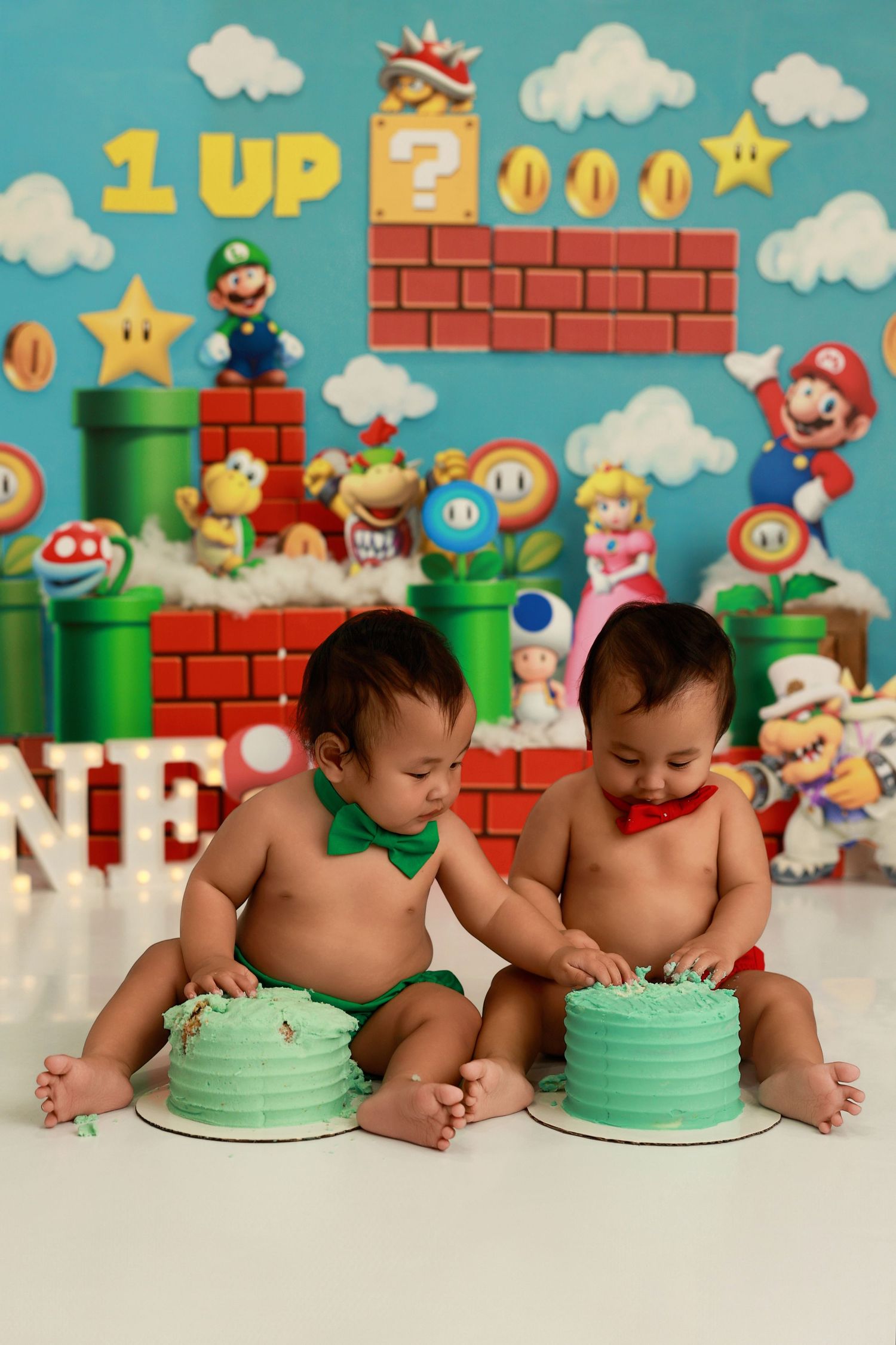 Super Mario themed cake smash photo session with colorful backdrop featuring game characters and decorations.