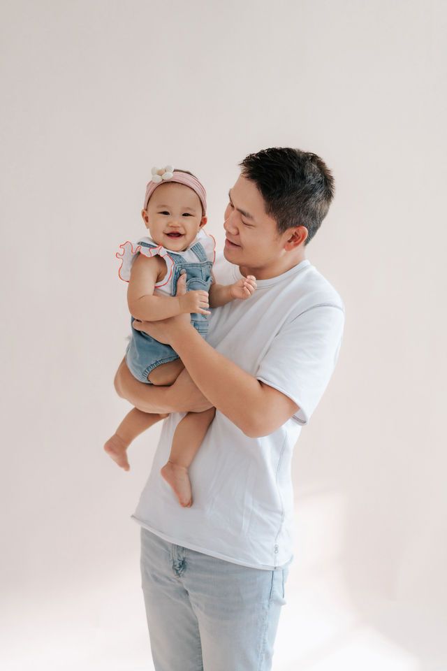 A parent and child share a joyful moment playing together in warm sunlight by a window.一位家長和孩子在溫暖的陽光下，於窗邊玩耍，享受著快樂的時光。