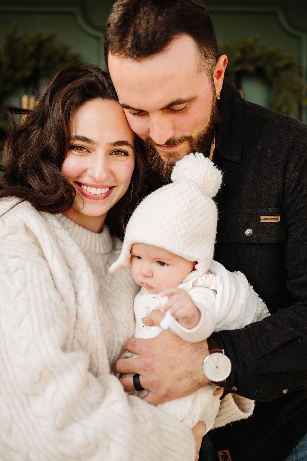 A tender family moment captured indoors with everyone wearing white and black winter clothing.