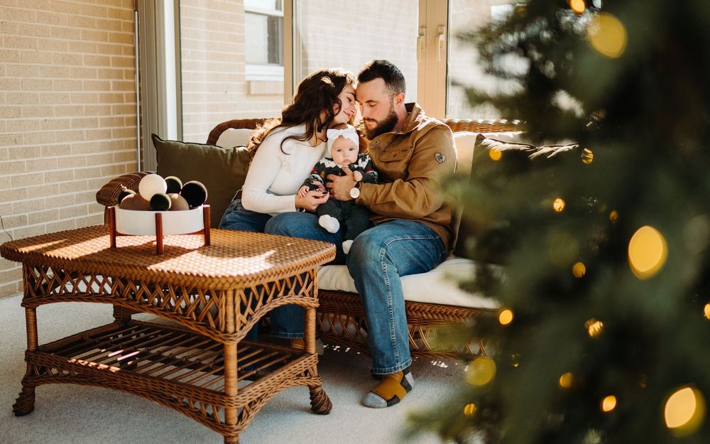 A wicker bench sits on a porch with twinkling Christmas lights visible in the background.