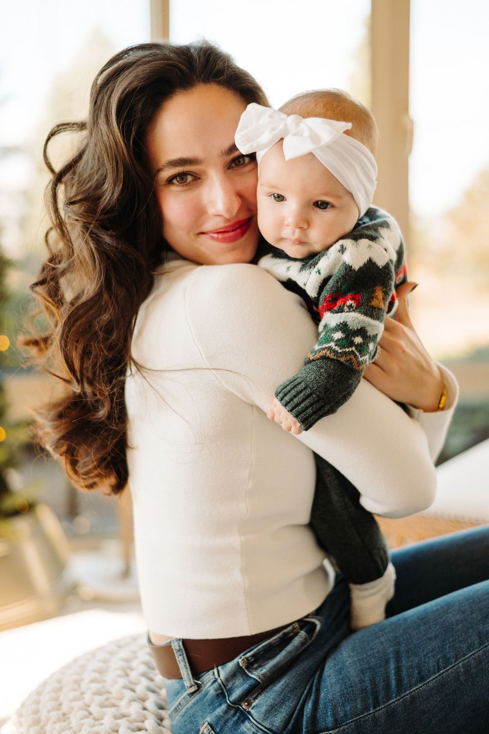 A cozy indoor scene with winter decor features a white sweater and soft lighting by a window.