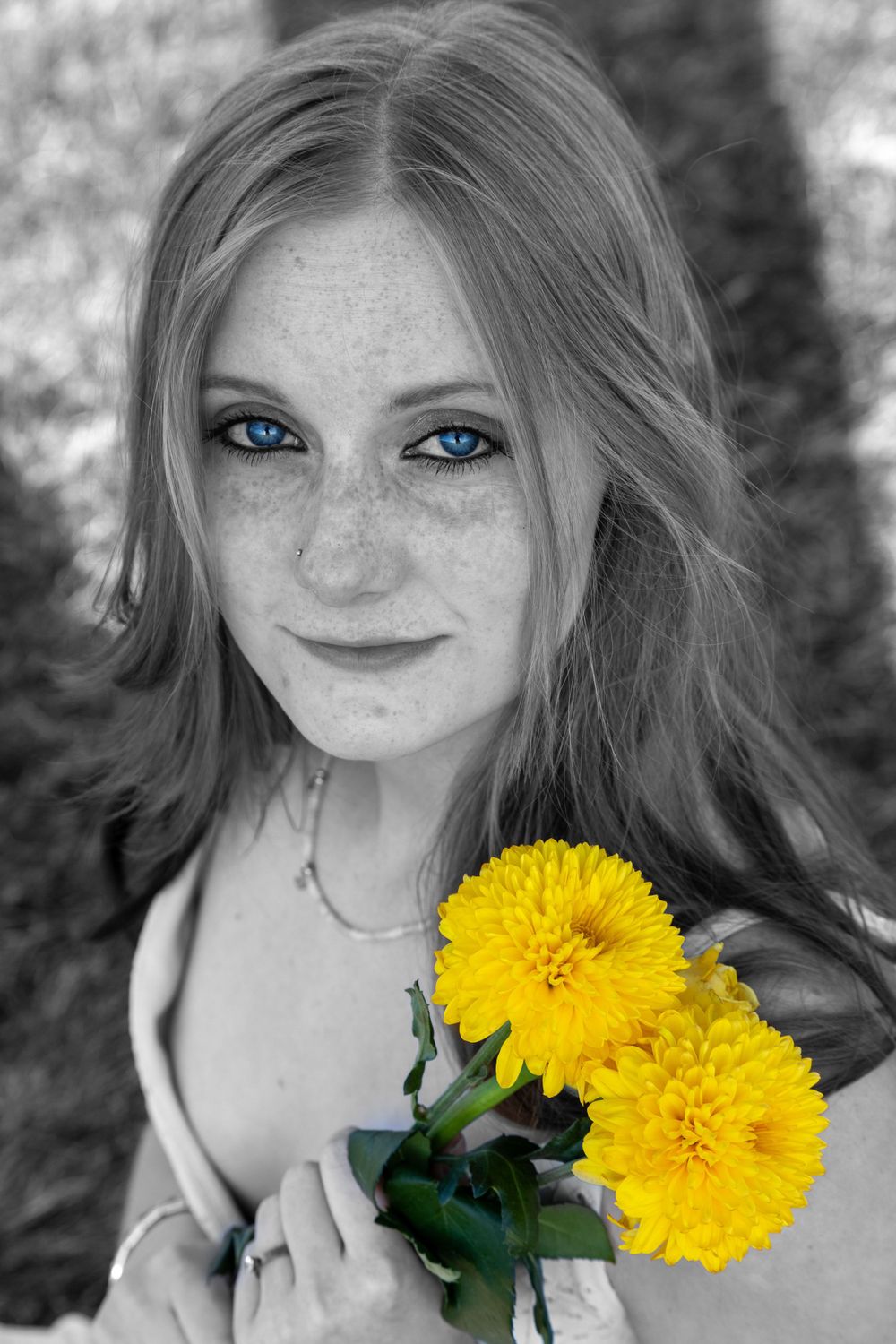 Senior poses outdoor during the spring color pop creative edit focusing on her stunning blue eyes and beautiful yellow flowers.