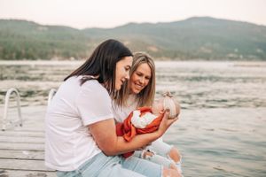 A heartwarming moment shared on a lakeside dock with a small baby wrapped in orange blanket.