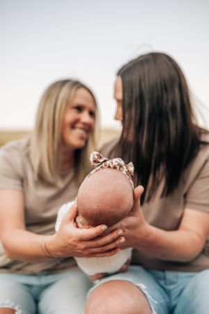 Intimate family moment with sleeping baby outdoors against natural background.