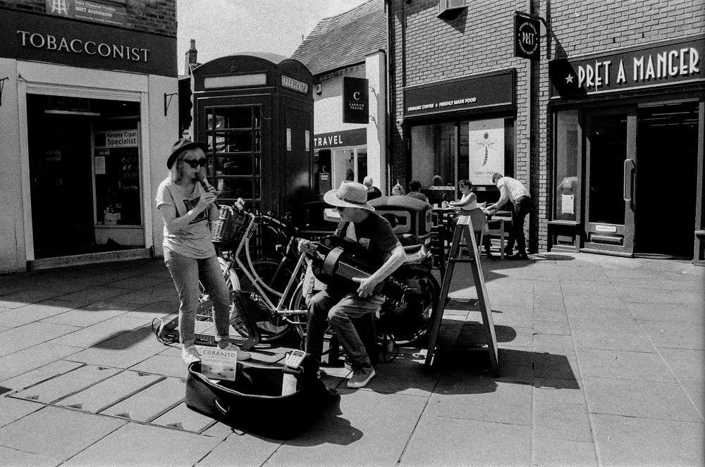 Street musicians performing with instruments on a shopping street.