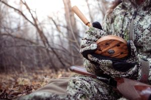 Hunting gear and equipment resting on fallen tree trunk in winter woods.