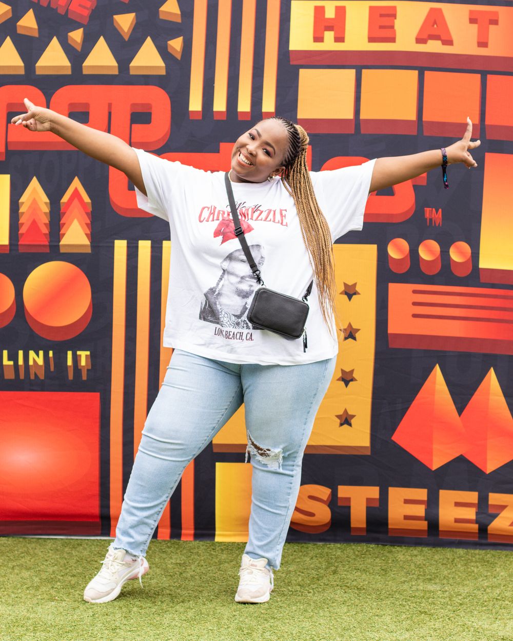 Person posing expressively against a vibrant orange and red geometric patterned wall backdrop.