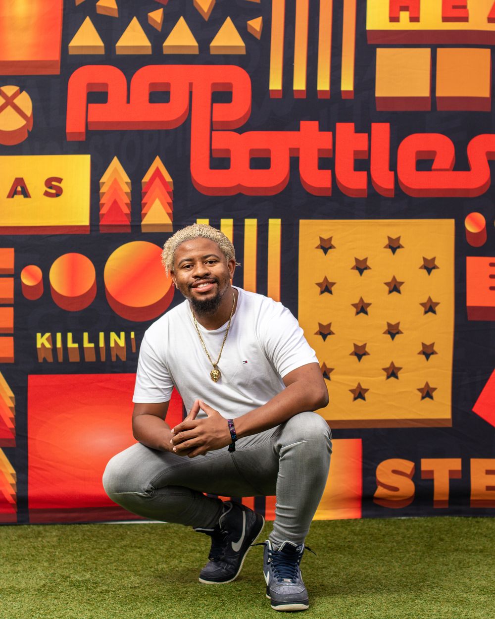 Casual portrait shot against vibrant orange and red geometric backdrop.