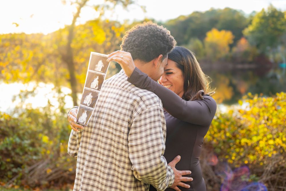 A couple embraces during a golden hour photoshoot surrounded by vibrant yellow wildflowers at sunset.
