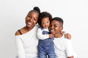 Three siblings smiling together in studio portrait by Menifee baby photographer.